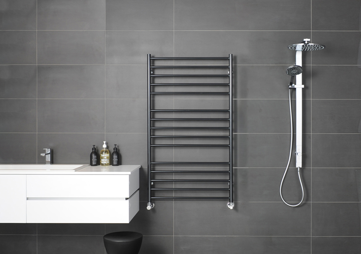 Chrome heated towel rail on a dark tiled bathroom wall